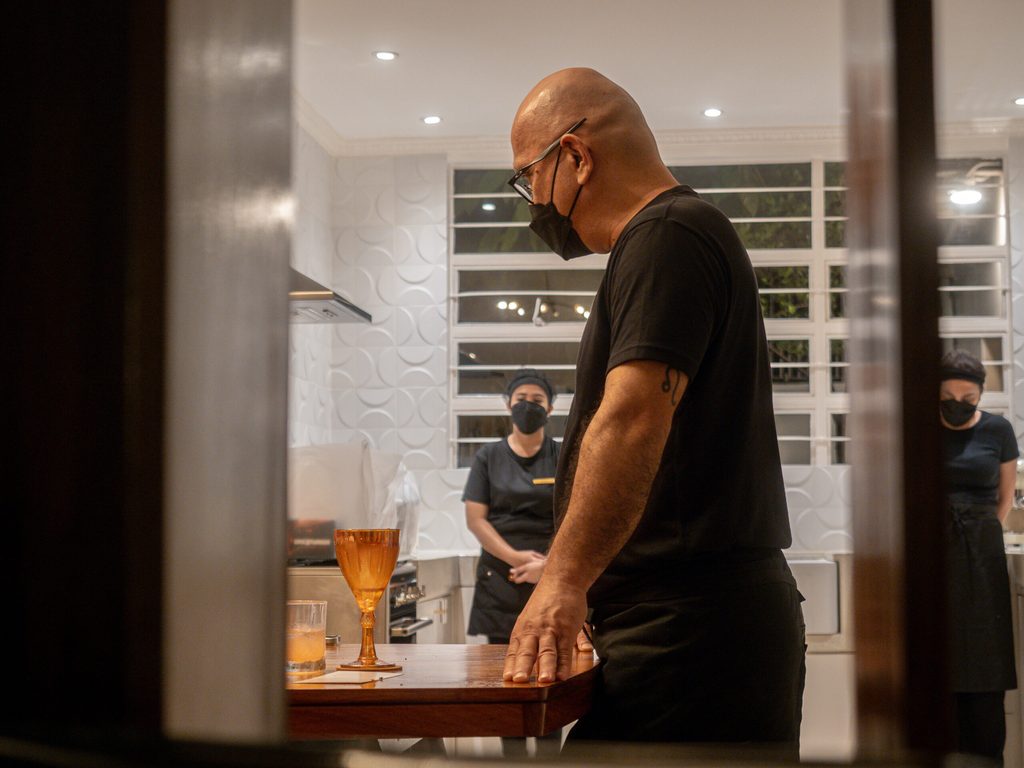 Chef Nats in the open kitchen at 61 Orange with amber glassware in foreground
